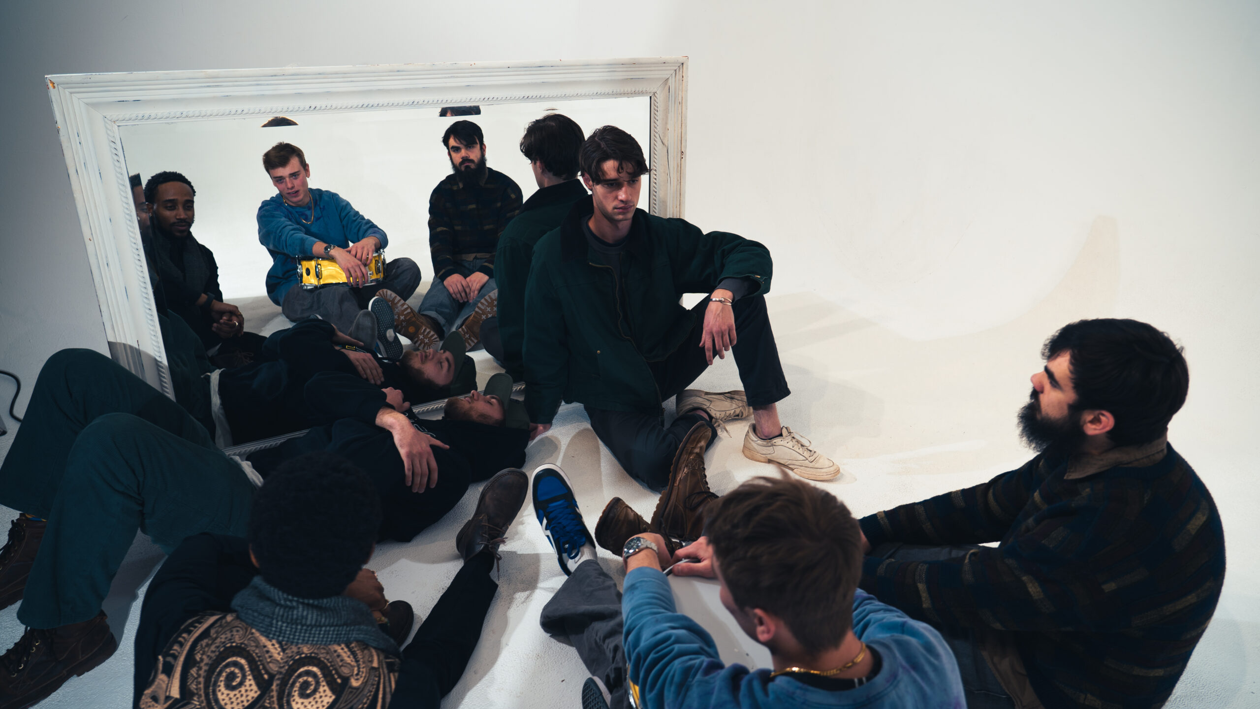 Iies sitting on floor in a white room in front of a mirror